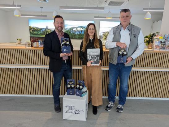 Stolz präsentieren v. l. n. r. Erster Bürgermeister Mario Schönwald, Tourismusleiterin Anne Schneider und Hans-Josef Stich, Werkleiter der Obermain Therme, das Jubiläumsmagazin „25 Jahre staatlich anerkanntes Heilbad“ sowie das eigens gebraute Jubiläumsbier im praktischen 4er-Träger. Foto: Tourist Information Bad Staffelstein-Carolin Böhmer